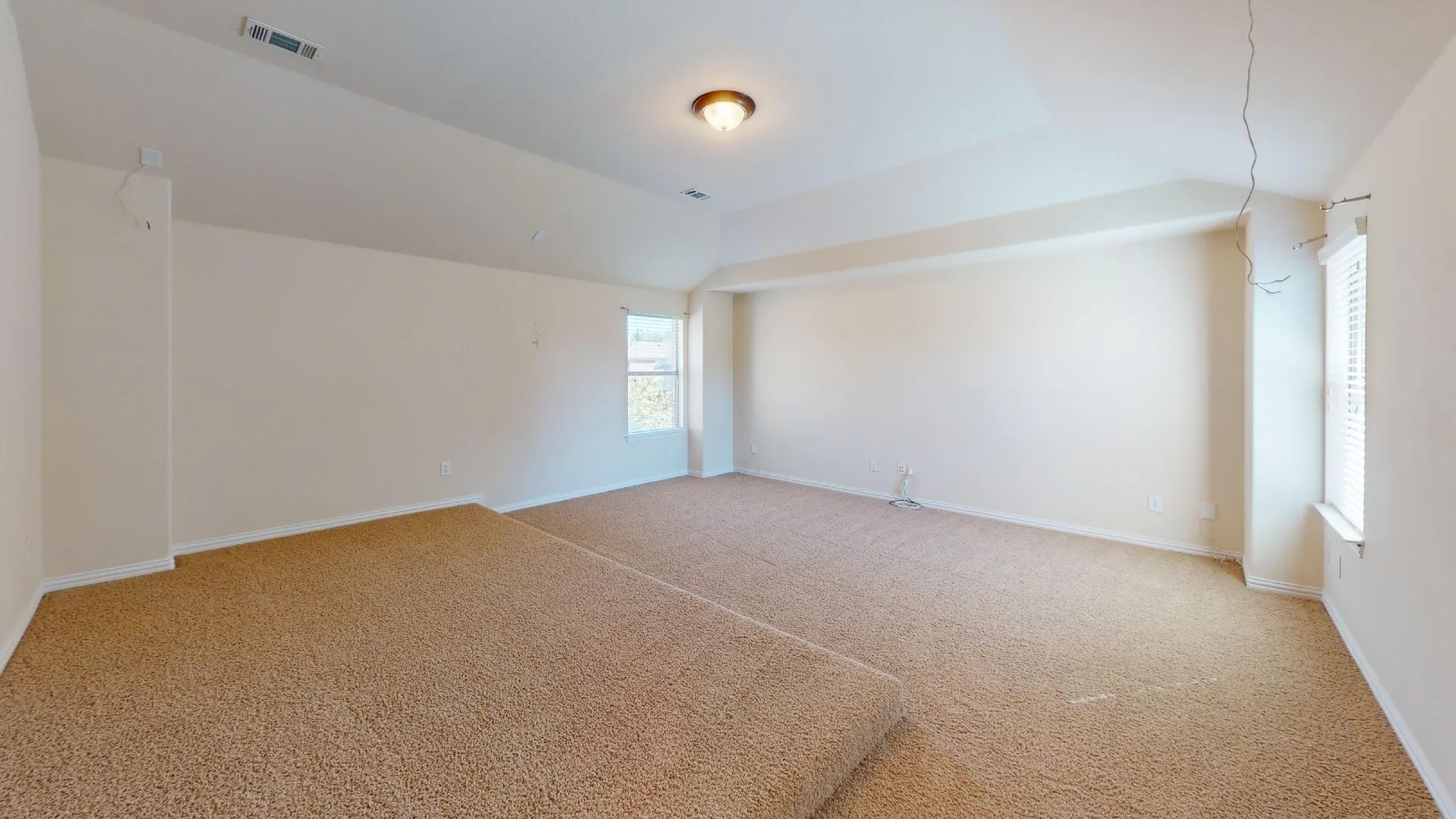 Interior space featuring a vaulted ceiling, neutral wall tones, carpeted flooring, and multi-level floor partitioning