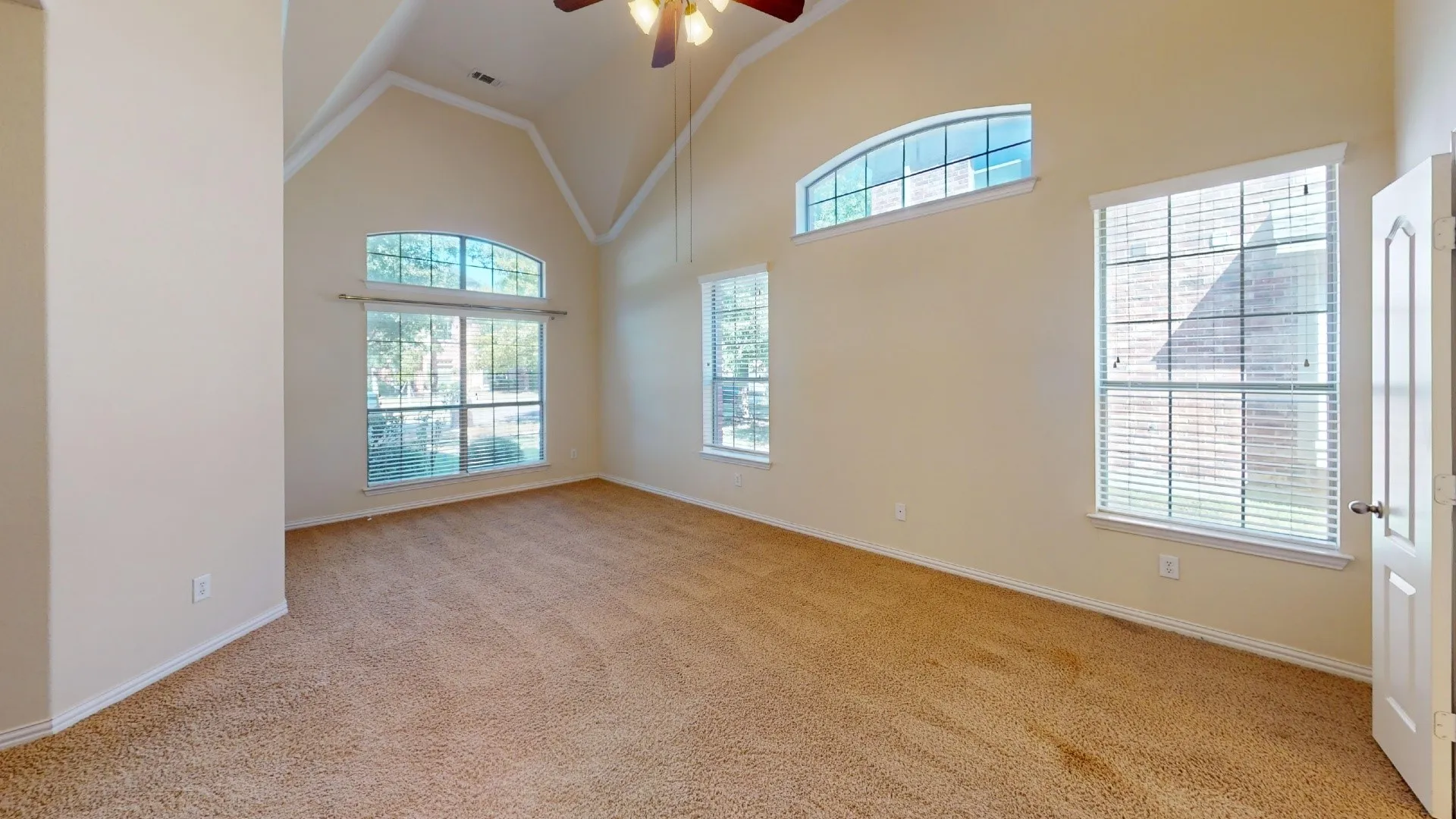 Vaulted ceiling featuring a central hanging light fixture, neutral wall color, and multiple arched windows