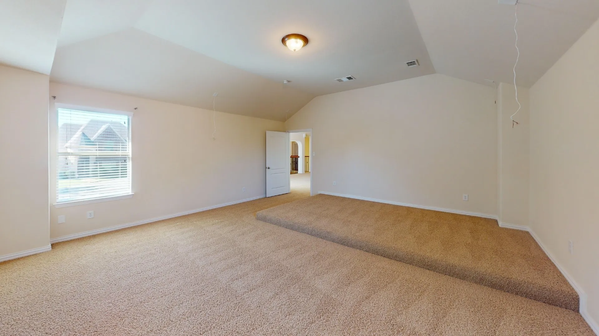 Vaulted ceilings, carpeted flooring, raised platform area, and flush-mount lighting