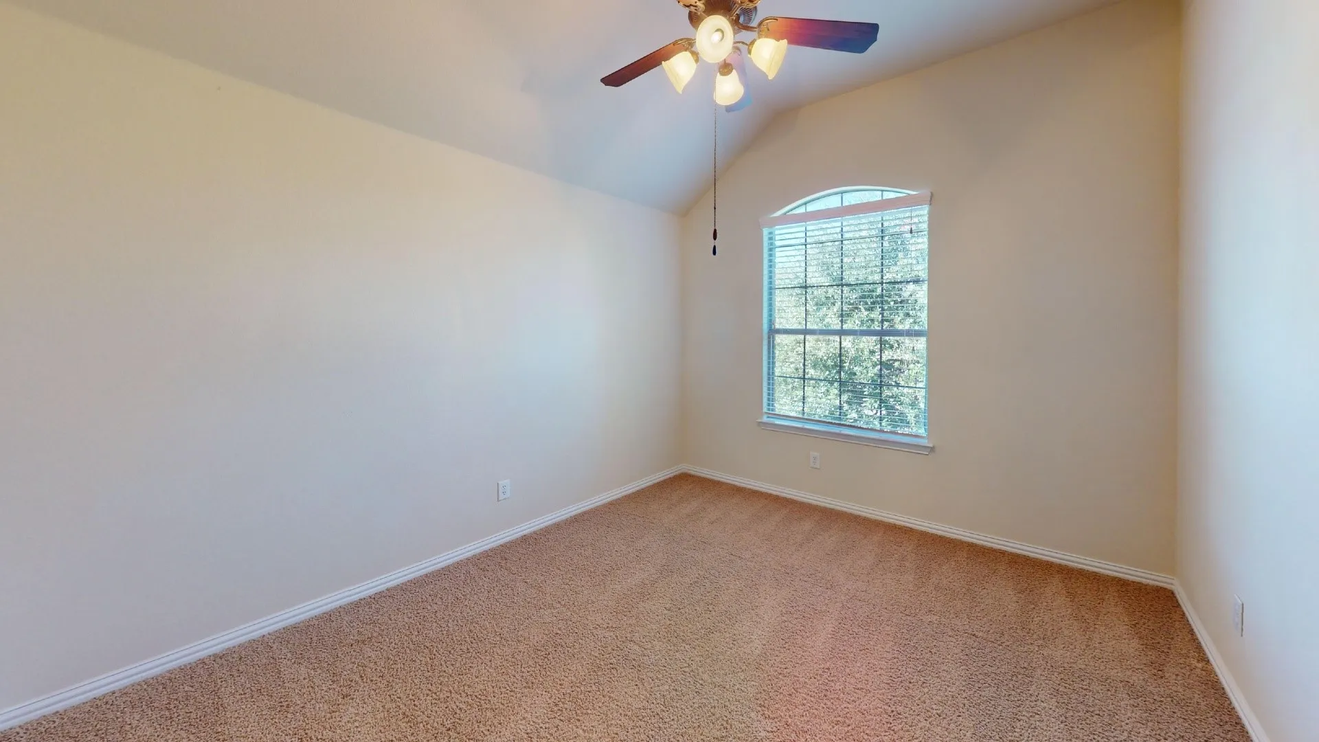 Vaulted ceiling, arched window with grid mullions, and ceiling-mounted light fixture with a fan