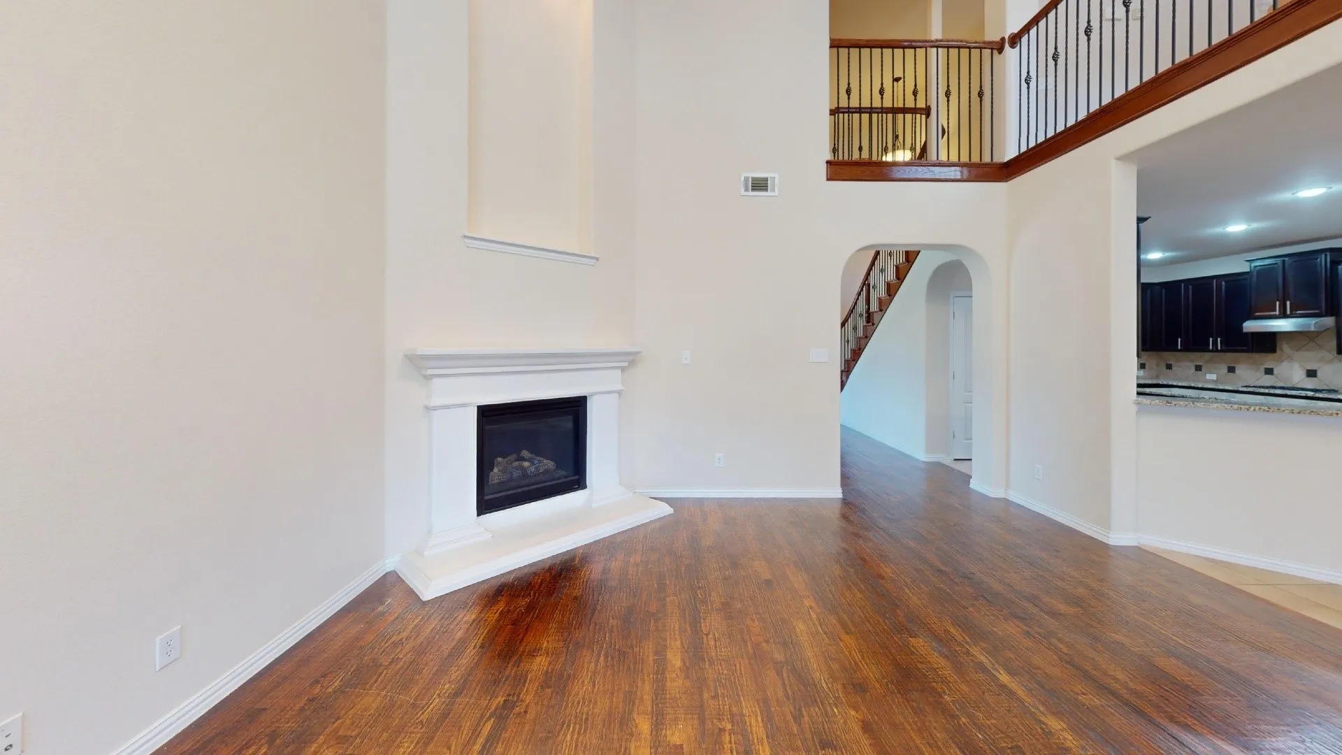 Double-height ceiling, wood-finish flooring, masonry fireplace with mantel, arched passageway, and second-level mezzanine railing