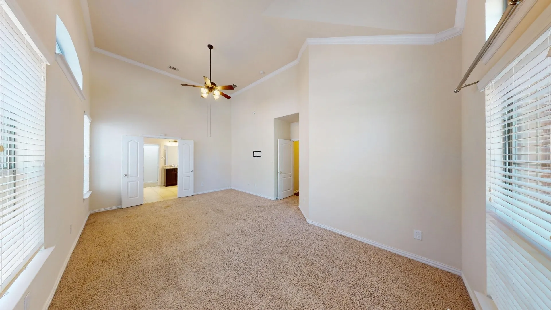 Vaulted ceilings, carpeted flooring, multi-pane windows with horizontal blinds, and a ceiling fan with integrated lighting