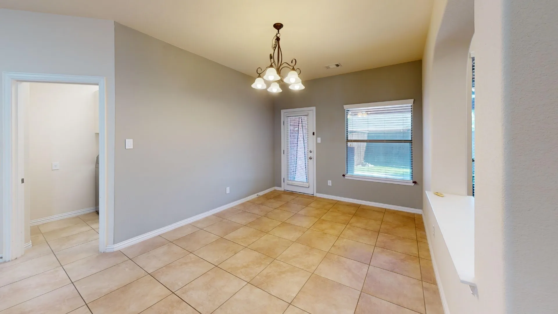 Ceramic tile flooring, decorative multi-light chandelier, recessed doorway entry, and arched architectural wall detail