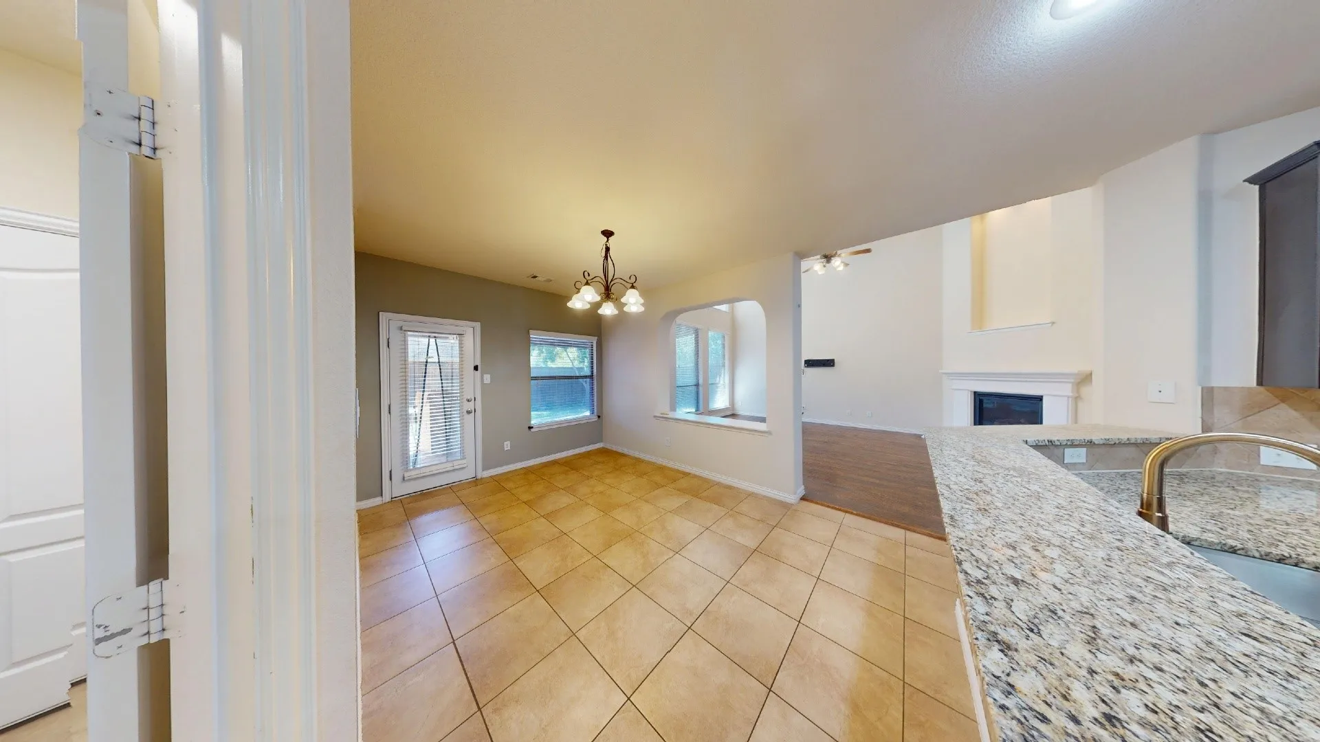 Kitchen featuring a stone-surface breakfast bar, ceramic tile flooring, arched wall cutouts, a multi-light chandelier, and a gas fireplace with a decorative mantle