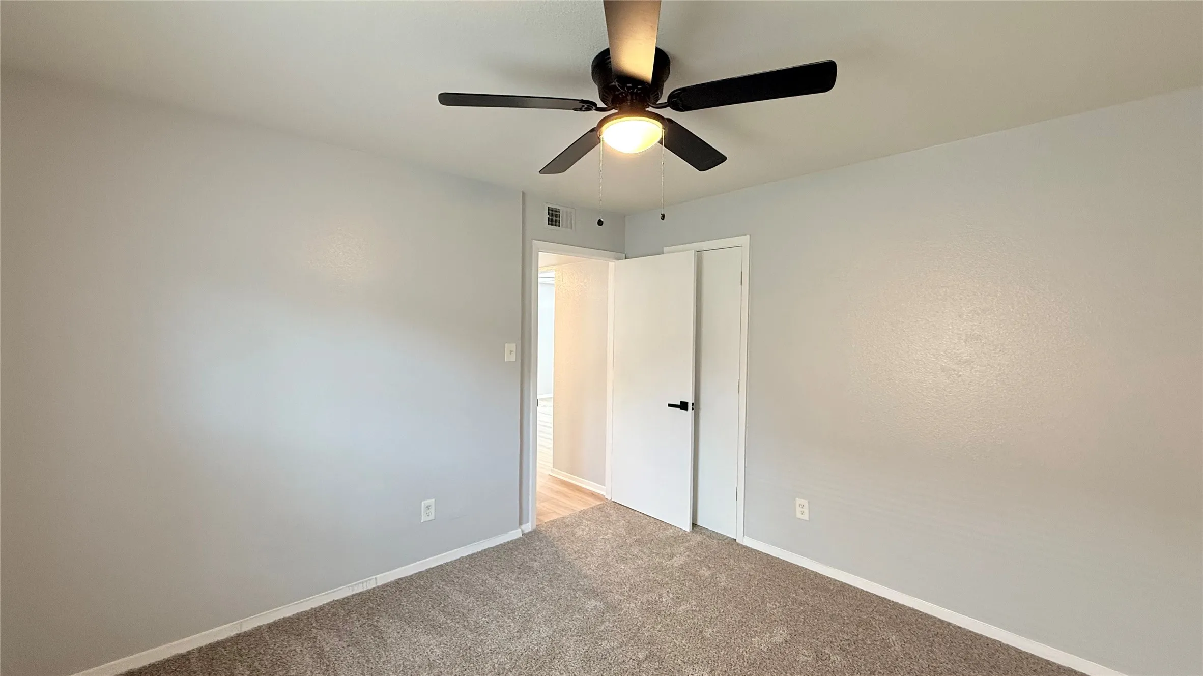 Room featuring neutral wall tones, plush wall-to-wall carpeting, and a multi-blade ceiling fan with integrated lighting