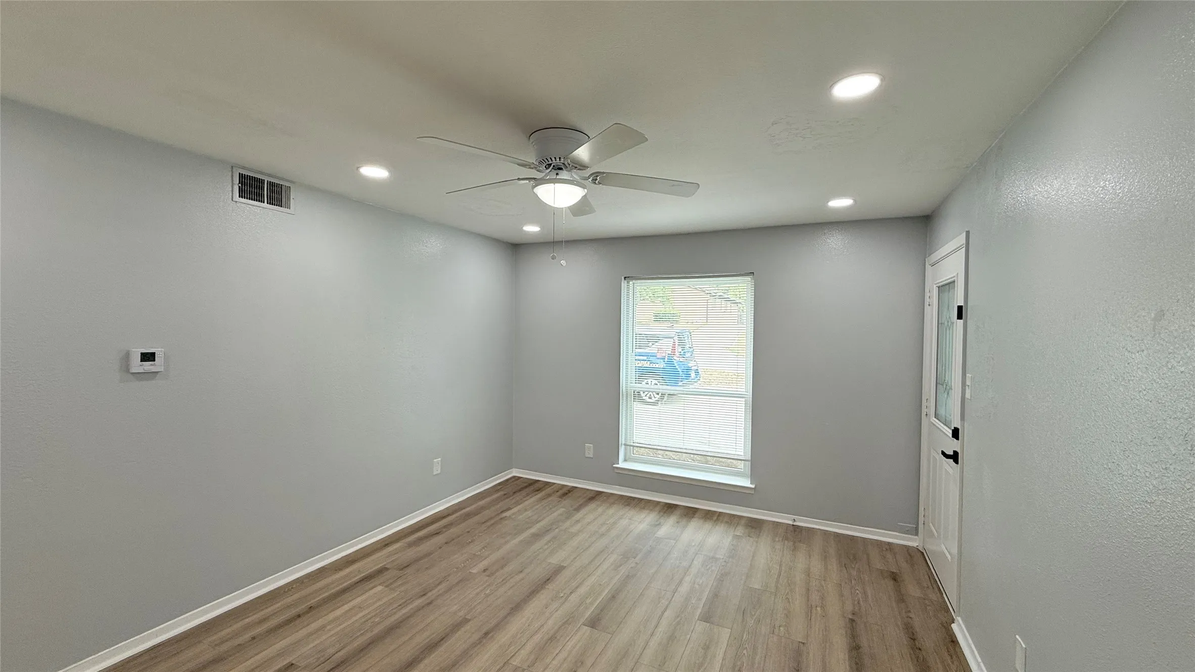 Interior space featuring wood-finish flooring, recessed lighting, a ceiling fan, a single-hung window, and an exterior door with glass detailing