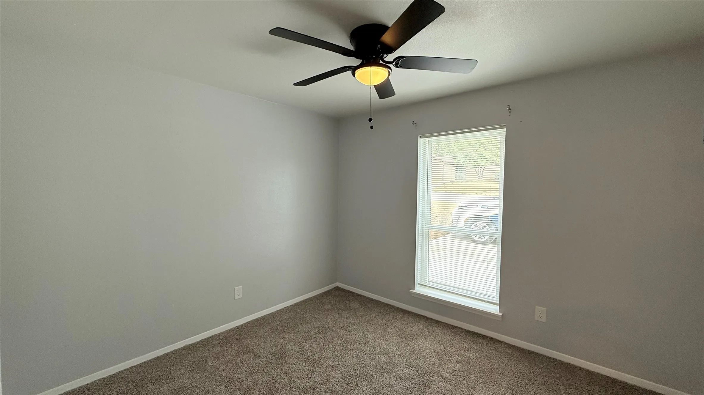 Neutral-toned walls, high-pile carpeting, and a central ceiling fan with integrated lighting