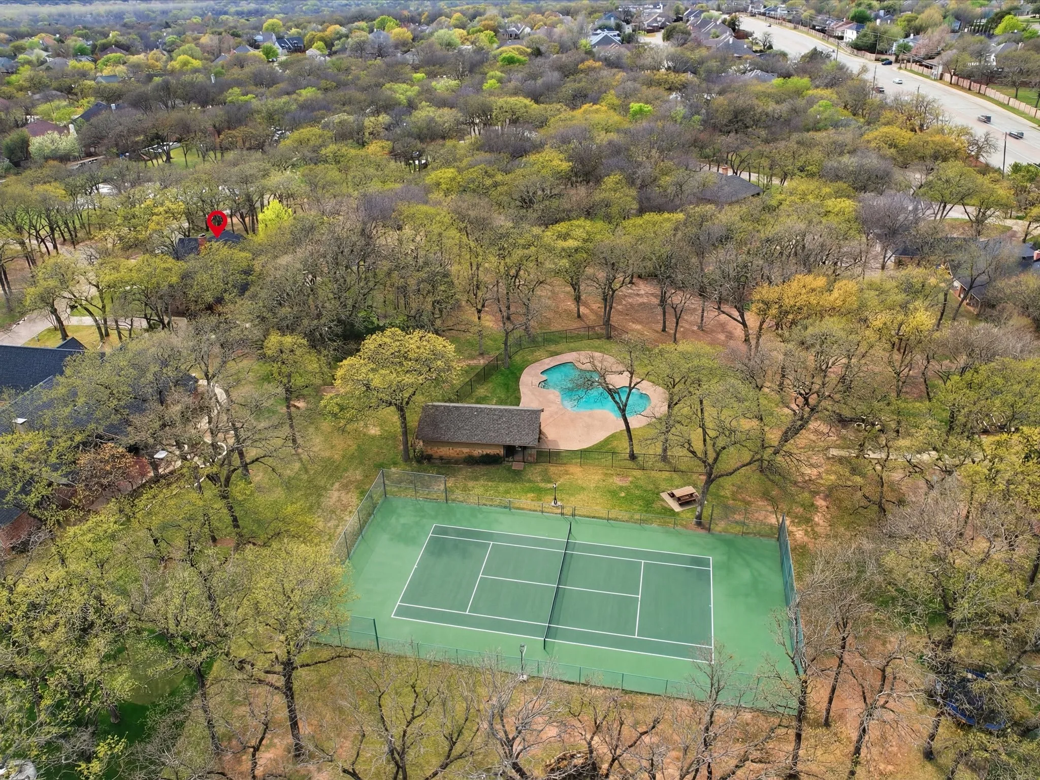 Expansive grounds featuring a fenced tennis court, swimming pool, detached structure, and mature trees
