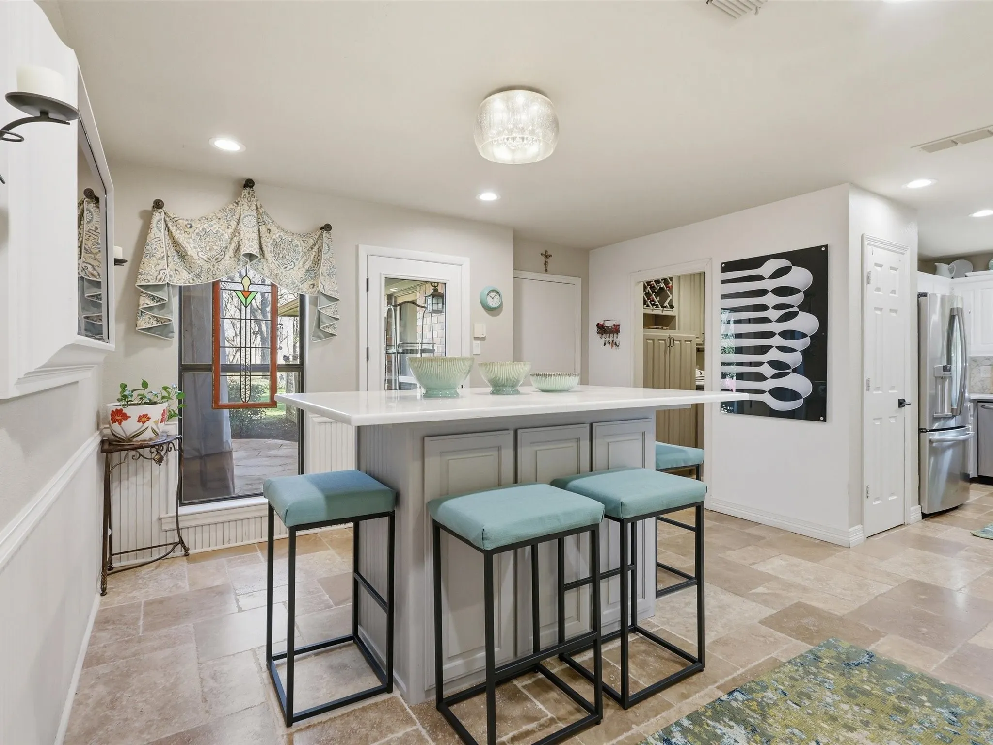Center kitchen island with neutral-toned cabinetry, light stone-surface countertop, recessed lighting, tile flooring, and decorative glass flush-mount fixture