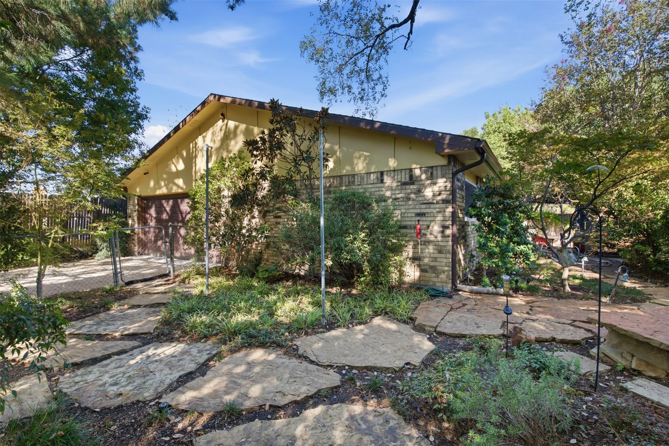 Exterior featuring a stone-clad facade, sloped roofline, and mature landscaping