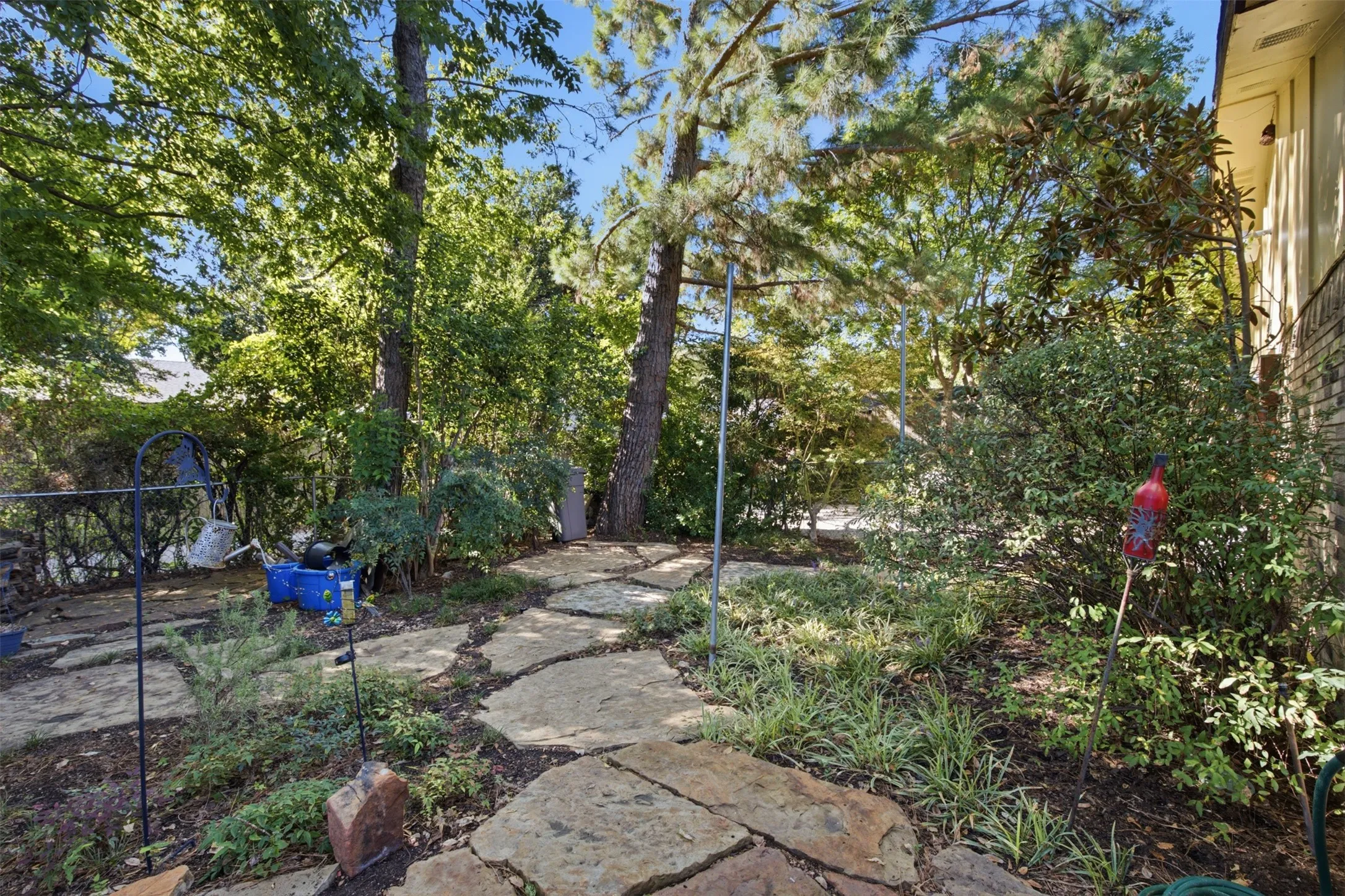 Stone pathway with natural rock elements, surrounded by mature trees and varied landscaping