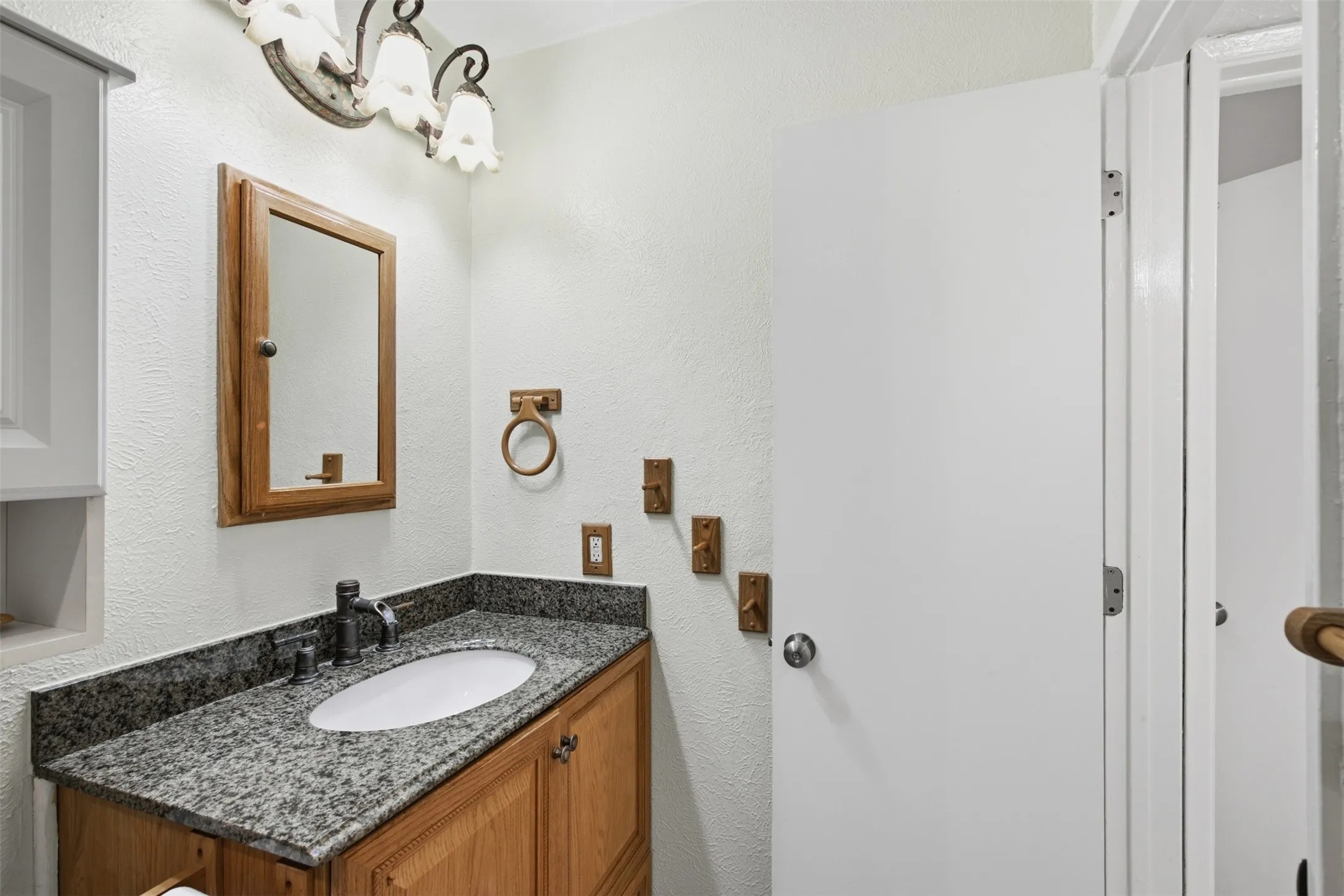 Vanity with a granite-style countertop, undermount sink, and wood-finish cabinetry