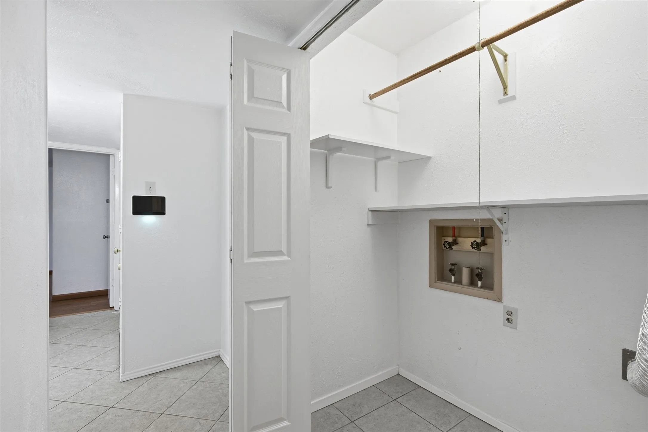 Laundry area with tile flooring, built-in shelving, and a hanging rod