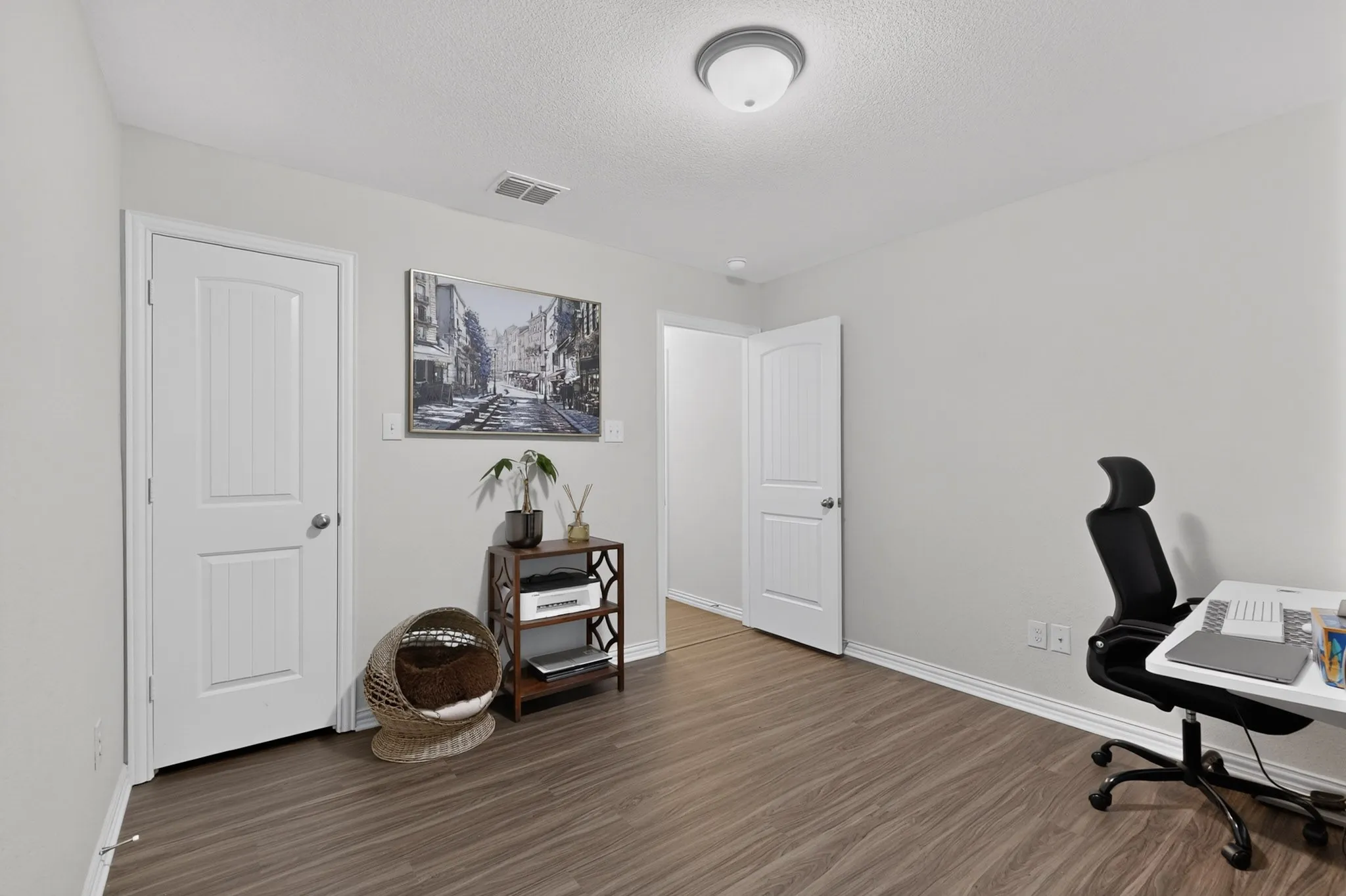 Neutral interior featuring wood-finish flooring, two-panel interior doors, and a ceiling-mounted flush-mount light fixture