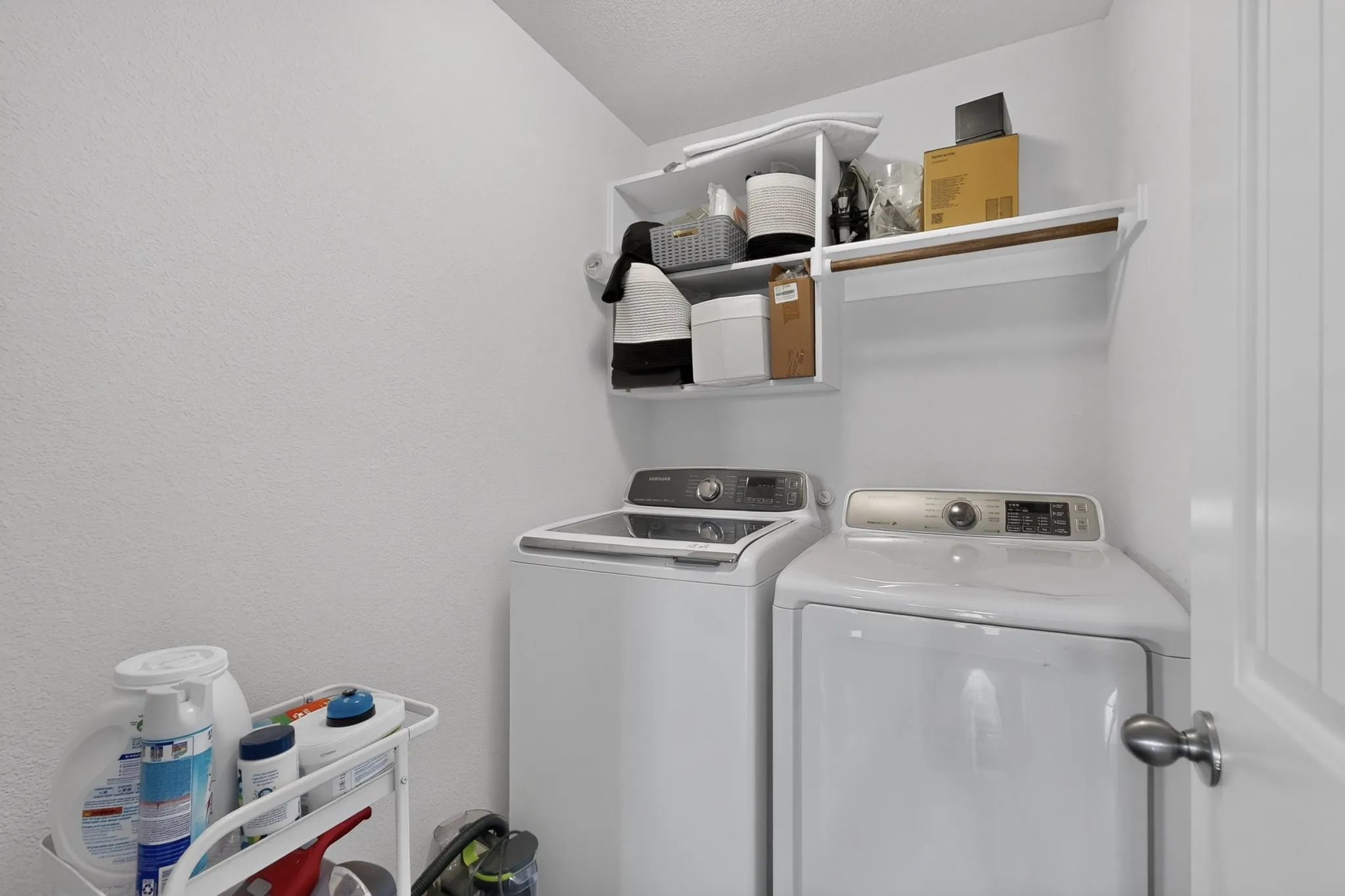 Laundry area featuring white built-in wall shelving with an integrated clothes rod