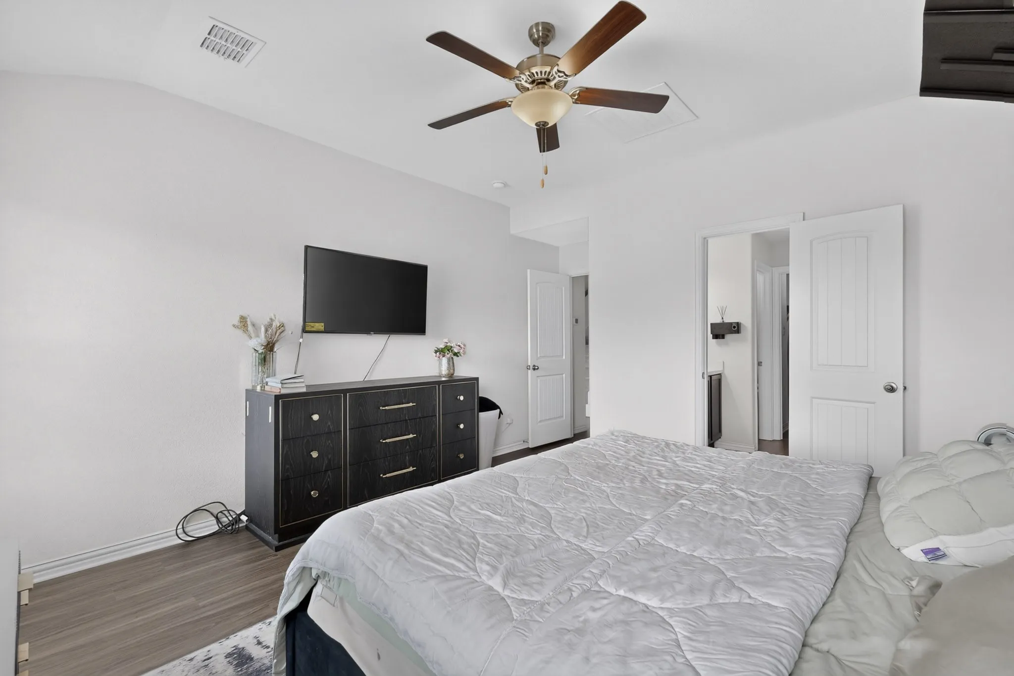 Vaulted ceiling featuring a central five-blade ceiling fan with integrated lighting and durable wood-finish flooring