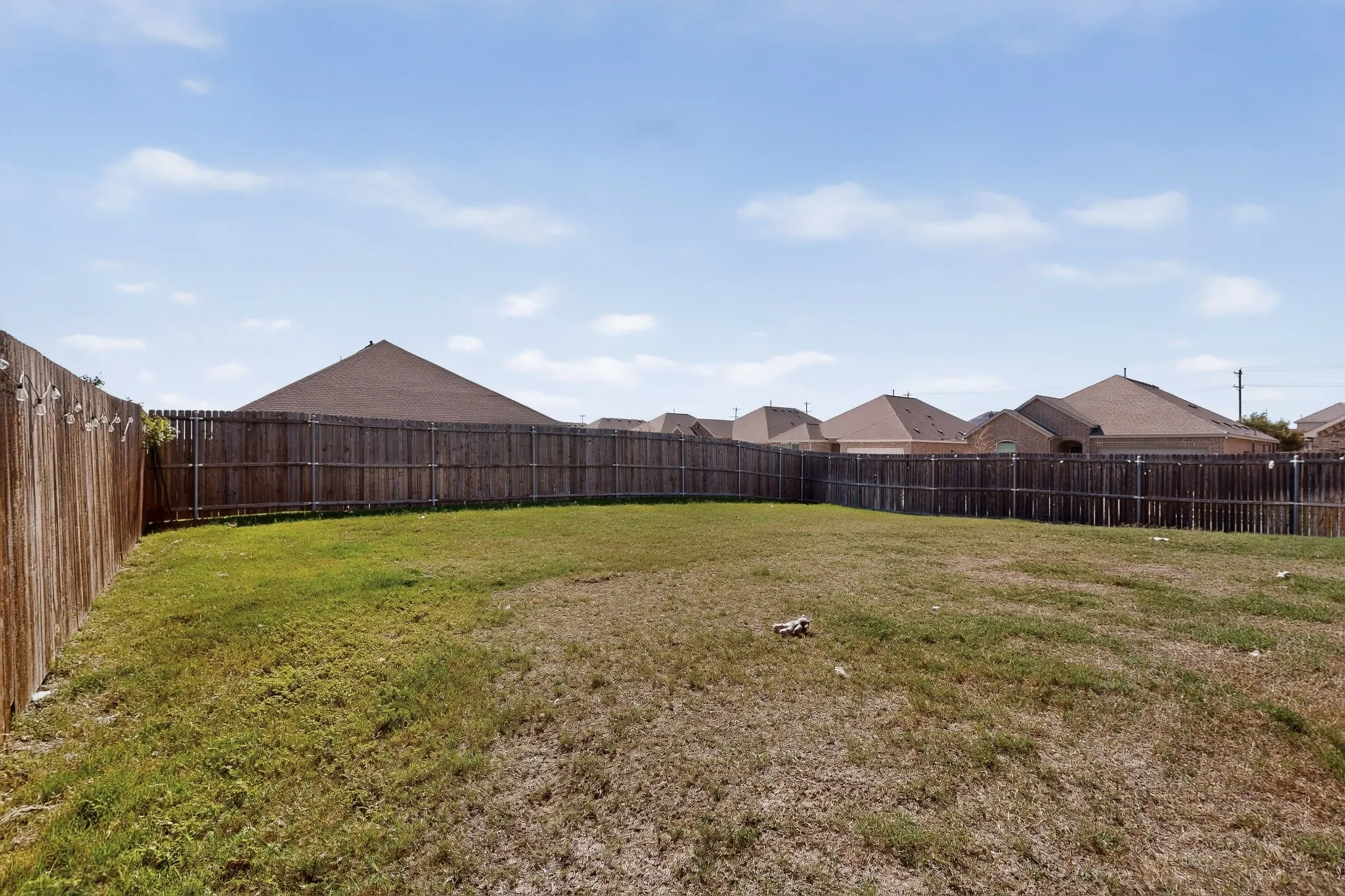 Open backyard featuring a manicured lawn and perimeter wood fencing