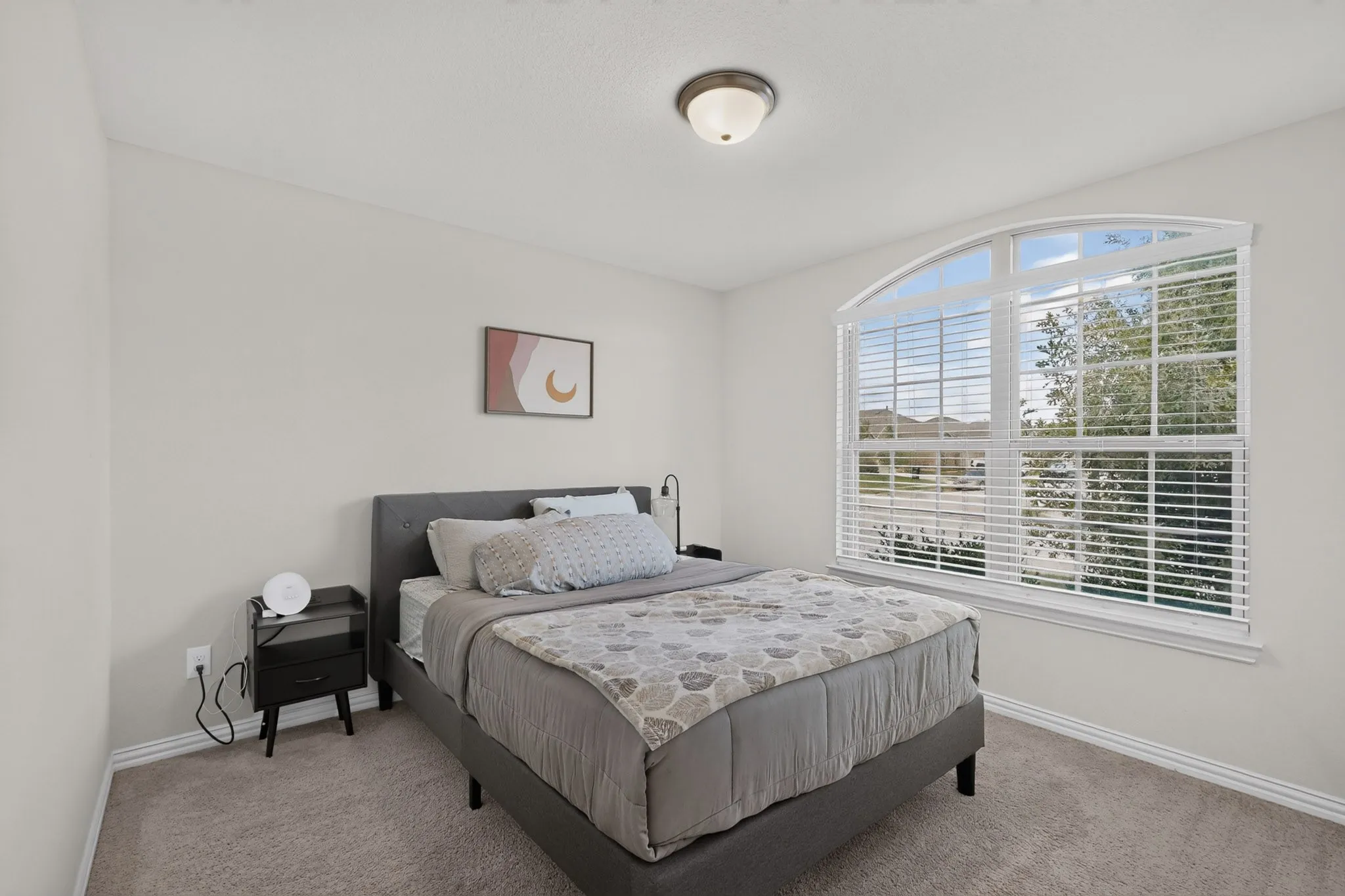 Neutral wall palette, carpeting, and a large window with a distinctive arched top transom