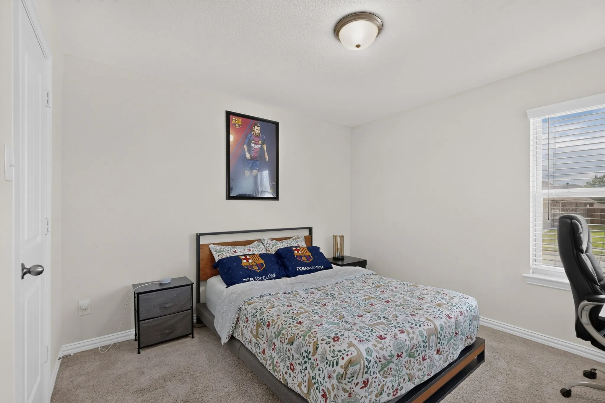 Neutral-toned bedroom featuring carpeted flooring, a single window with horizontal blinds, and a dome-style flush-mount ceiling light