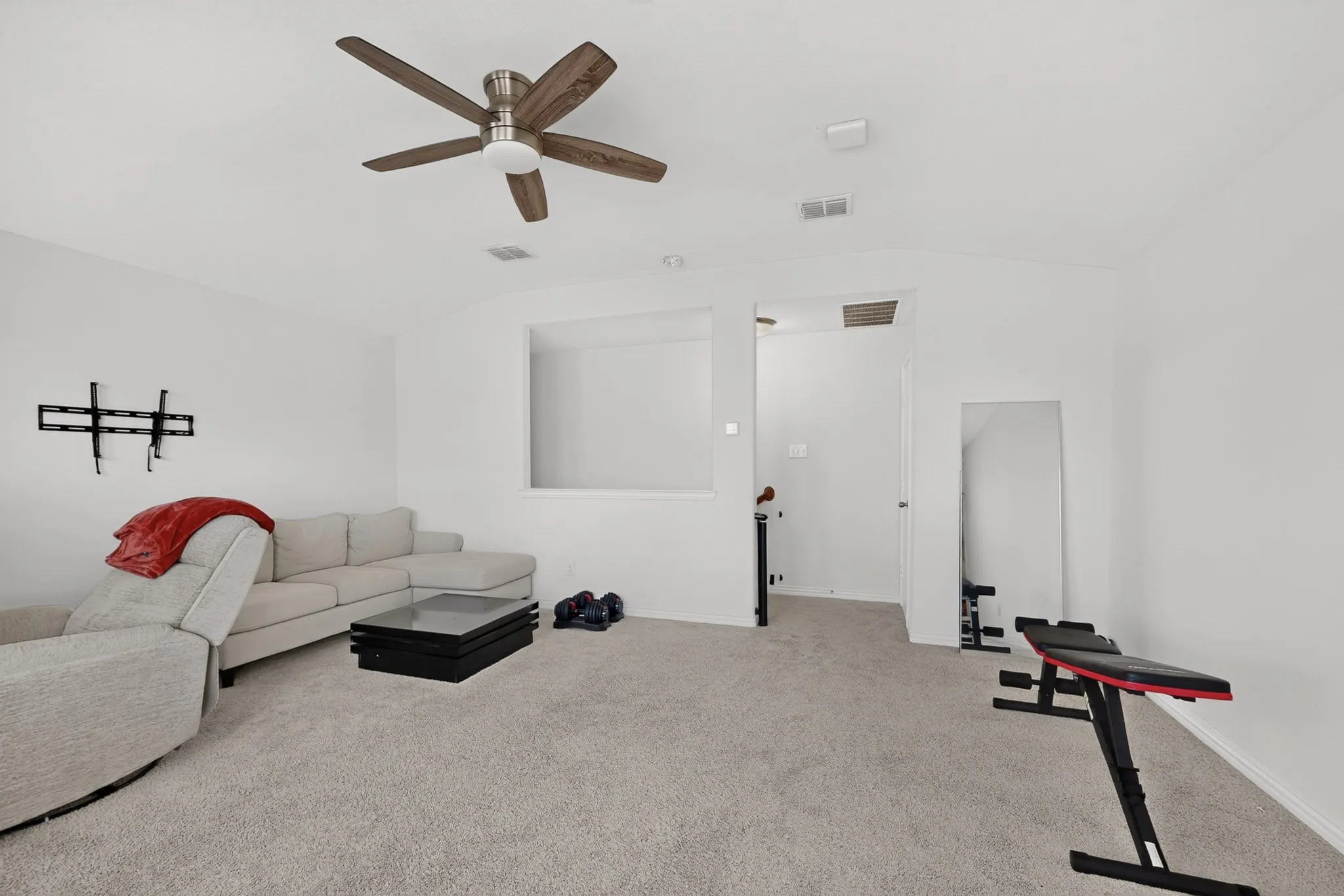 Interior space featuring carpeted flooring, a vaulted ceiling, and a ceiling fan with integrated light fixture