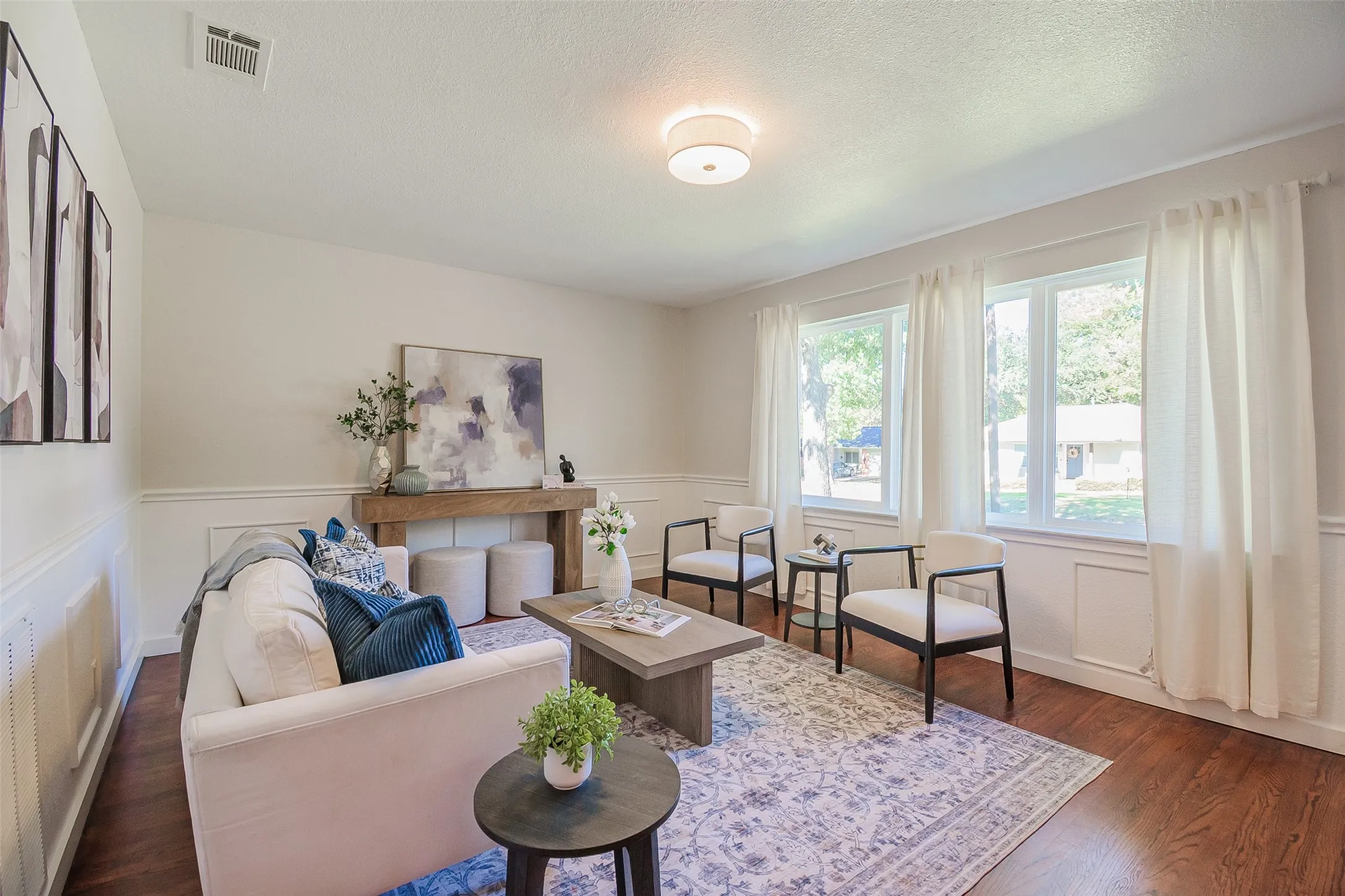 Living area featuring wood-finish flooring, wainscoting, and multi-pane windows with natural light