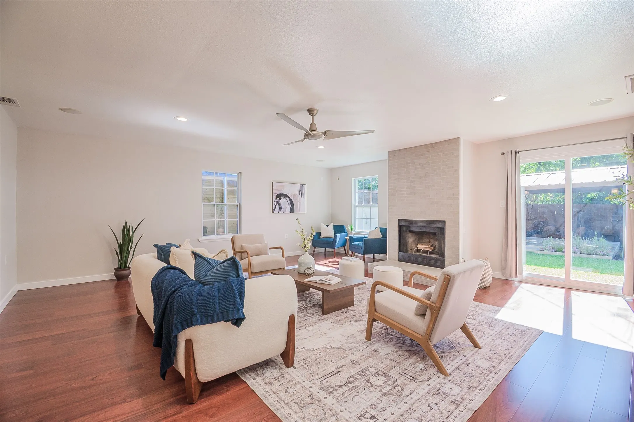 Living area featuring wood-finish flooring, a floor-to-ceiling fireplace with stone-style surround, recessed lighting, a ceiling fan, and sliding glass doors