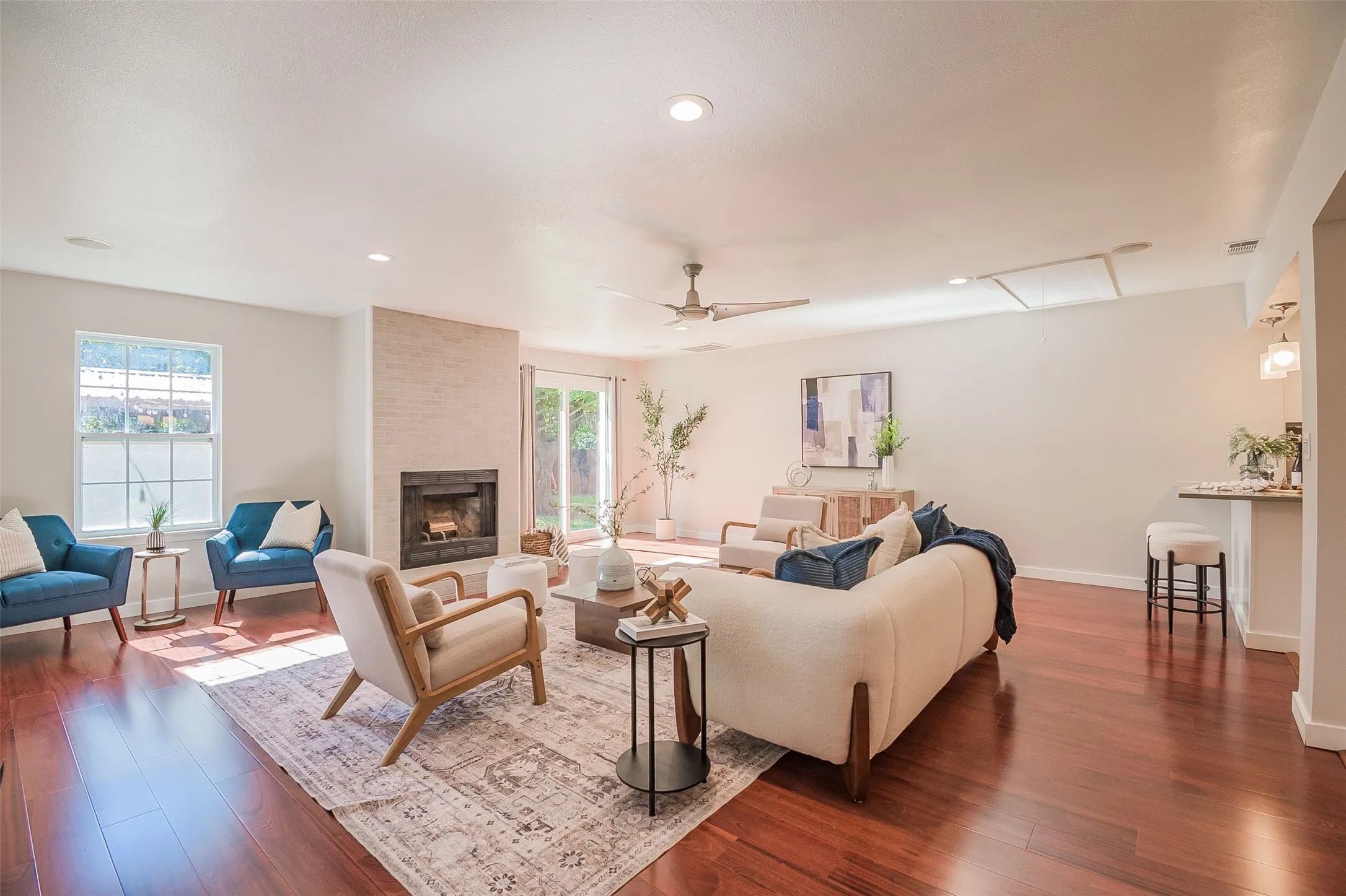 Living area featuring wood-finish flooring, a floor-to-ceiling masonry fireplace, recessed lighting, a ceiling fan, and glass sliding doors
