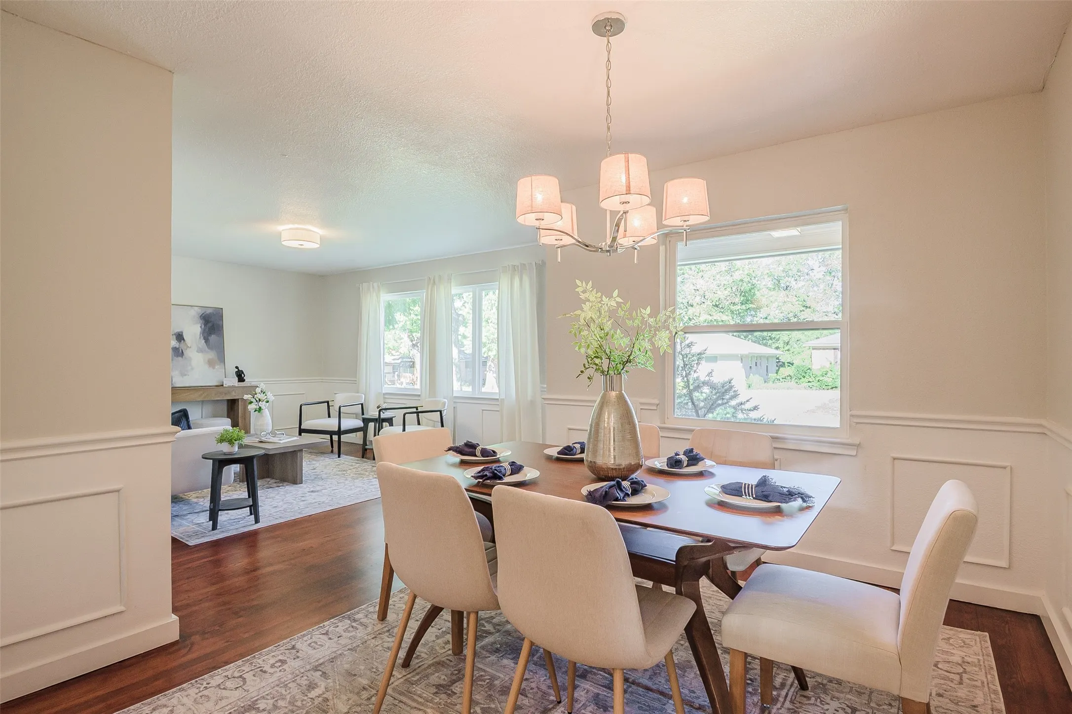 Dining area featuring wood-finish flooring, white wainscoting, and a multi-arm chandelier
