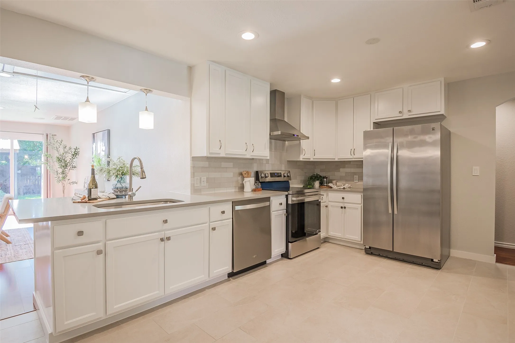 Kitchen featuring white shaker-style cabinetry, stainless steel appliances, a stone-composite countertop with an undermount sink, recessed lighting, and a subway-tile backsplash