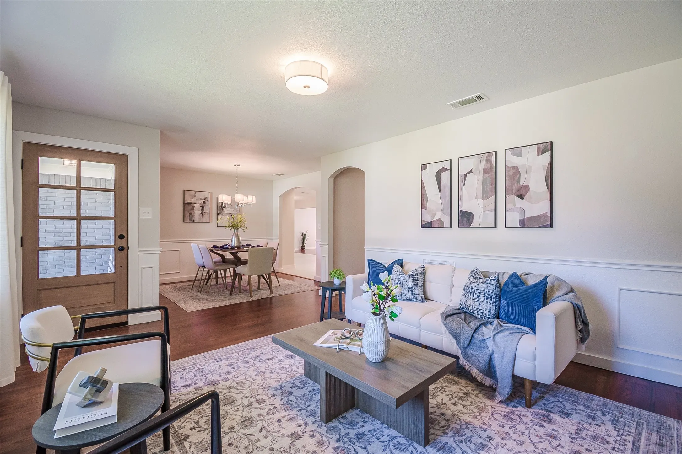 Wood-finish flooring, multi-pane glass entry door, arched interior doorway, and wainscoting