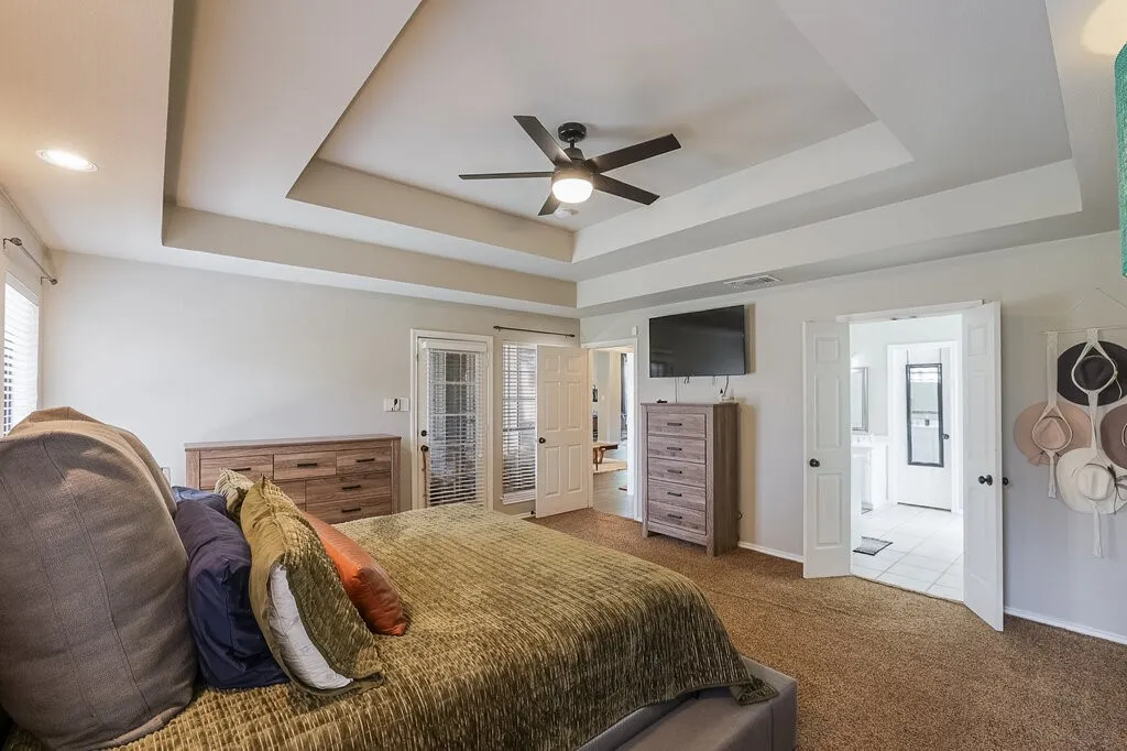 Tray ceiling with integrated recessed lighting, central ceiling fan, and double door entry