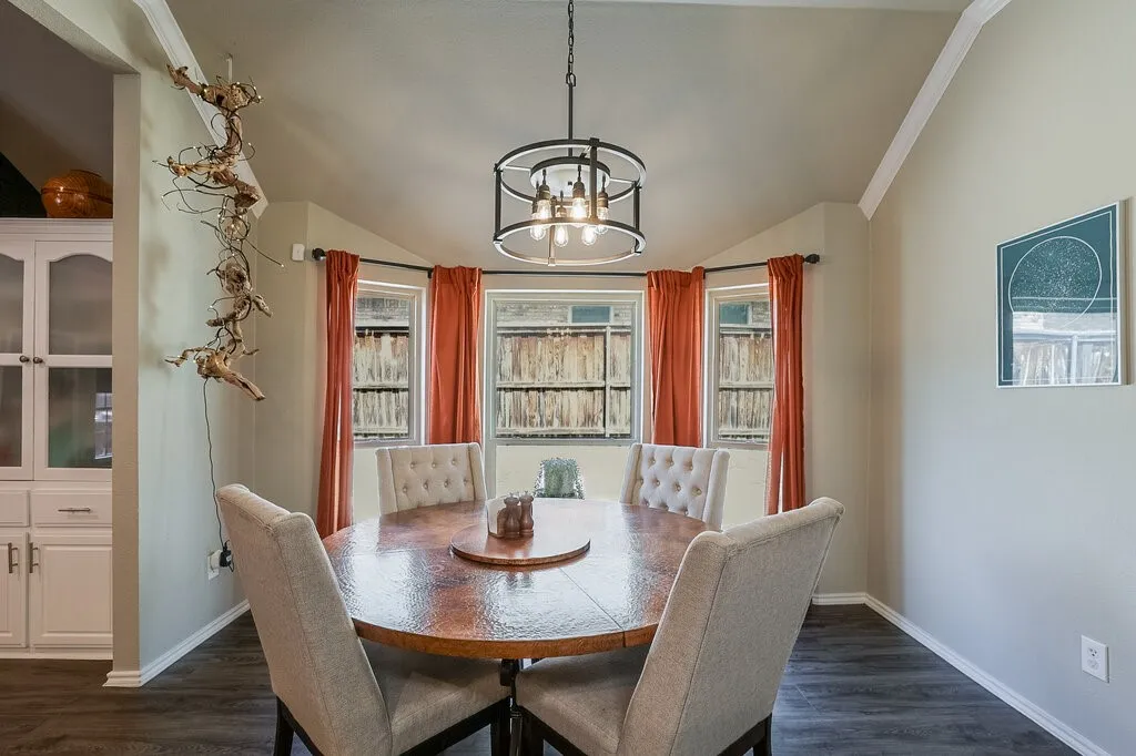 Vaulted ceiling, bay windows, built-in cabinetry, and a tiered metal chandelier