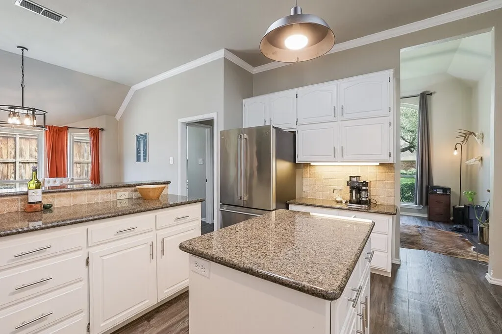 Kitchen featuring white cabinetry, stone countertops, a center island, stainless steel refrigerator, and wood-finish flooring