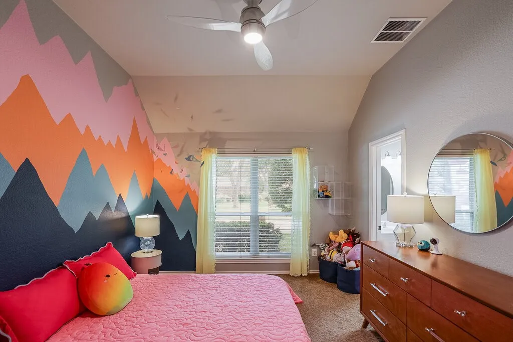 Vaulted ceiling with an integrated brushed-nickel finish ceiling fan and light fixture, featuring a window with horizontal blinds and a decorative mountain-range wall mural