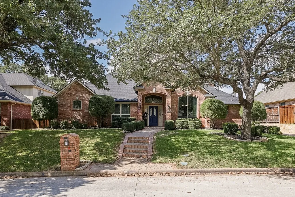 Brick exterior featuring a gabled roofline, arched entryway, multi-paned front door, and a brick-paved walkway with stone steps