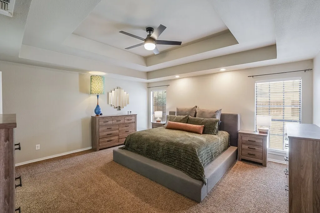 Tray ceiling with recessed lighting and a central ceiling fan, expansive window with horizontal blinds, and neutral wall-to-wall carpeting