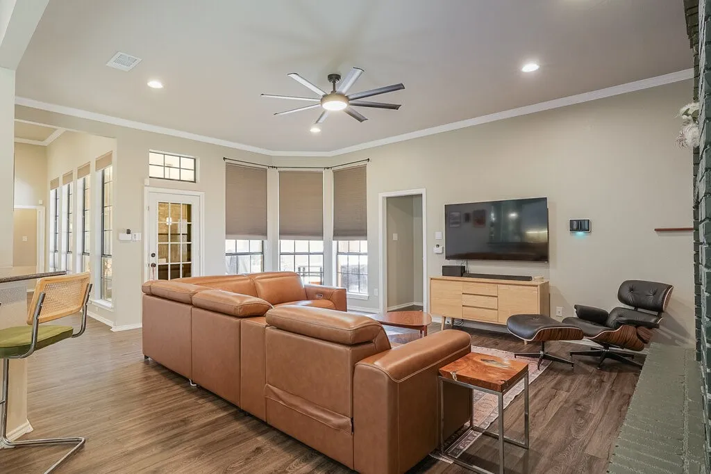 Living area featuring wood-finish flooring, a multi-blade ceiling fan, recessed lighting, and a bay window assembly with a transom light