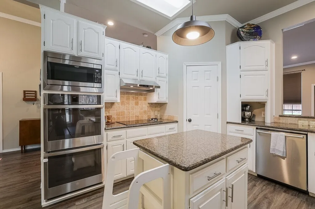 Kitchen featuring white cabinetry, stone-finish countertops, stainless steel wall-mounted double oven and microwave, stone tile backsplash, and a central island