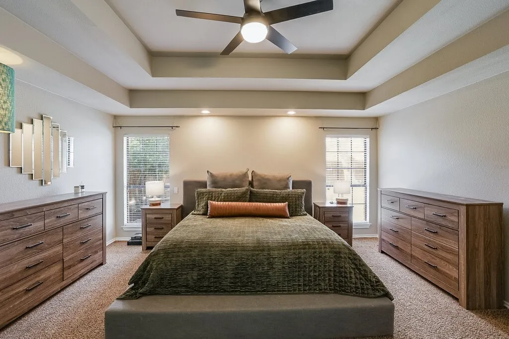 Tray ceiling with integrated recessed lighting, dual windows, and a central ceiling fan
