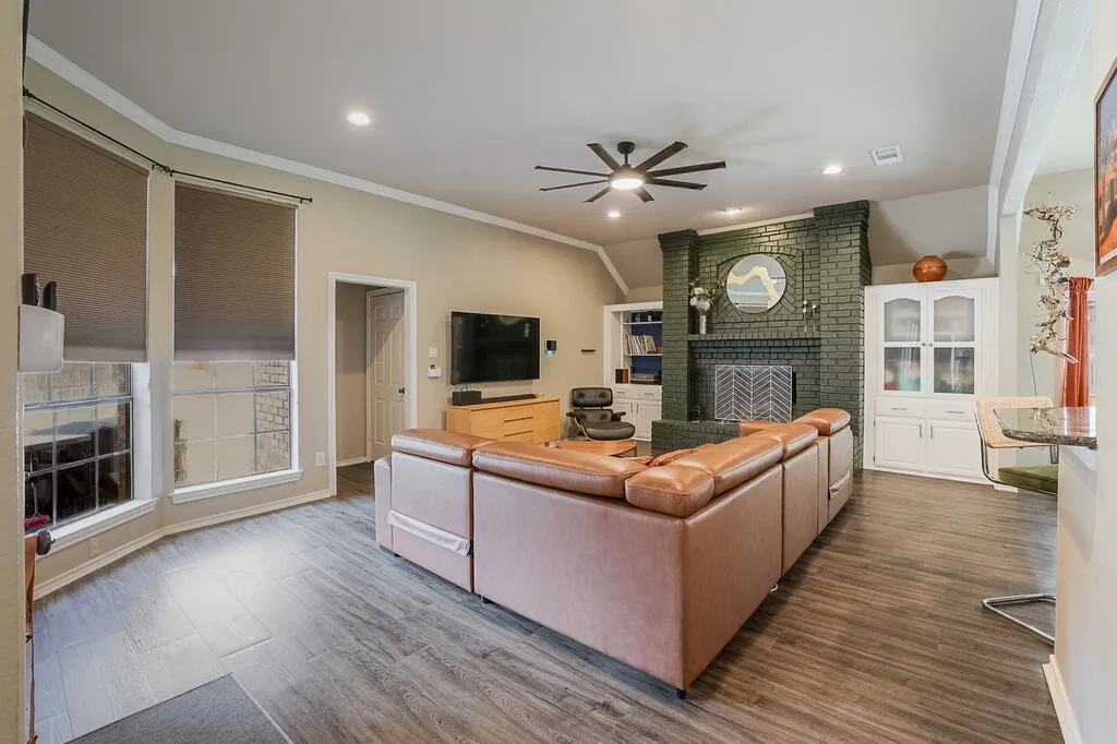 Living room featuring wood-finish flooring, a vaulted ceiling with a modern ceiling fan, recessed lighting, and a brick fireplace