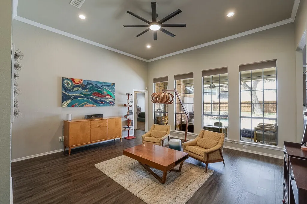High ceiling living space featuring wood-finish flooring, recessed lighting, a modern multi-blade ceiling fan, and large grid-pane windows
