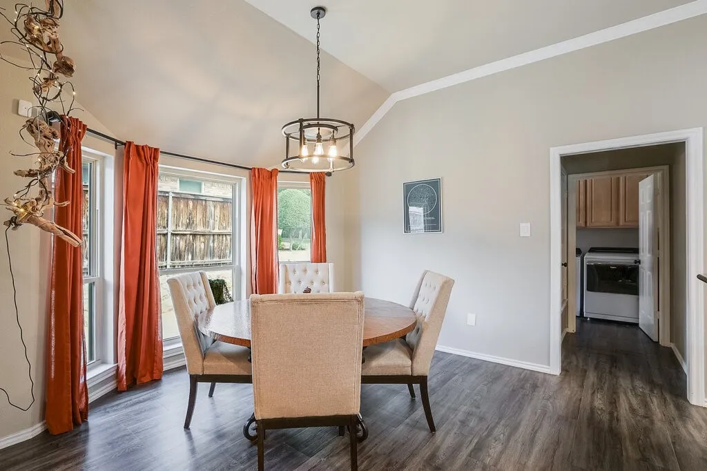 Vaulted ceiling featuring a drum-style chandelier, multi-pane windows, and wood-finish flooring
