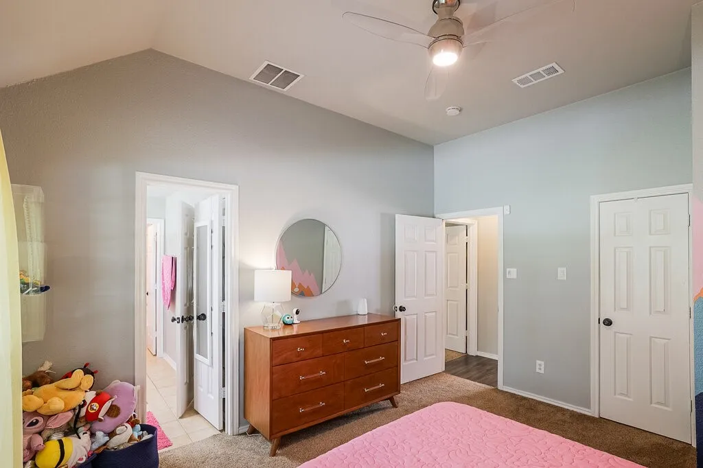 Vaulted ceiling featuring a central lighted ceiling fan, neutral wall paint, and multiple paneled interior doors
