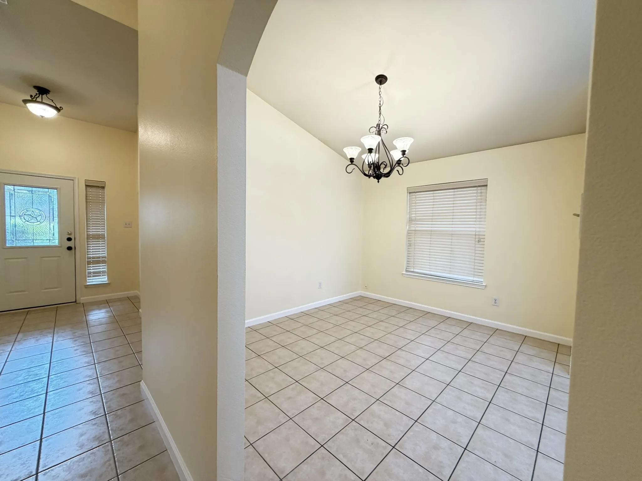 Ceramic tile flooring, arched entryways, multi-light iron chandelier, and neutral wall tones