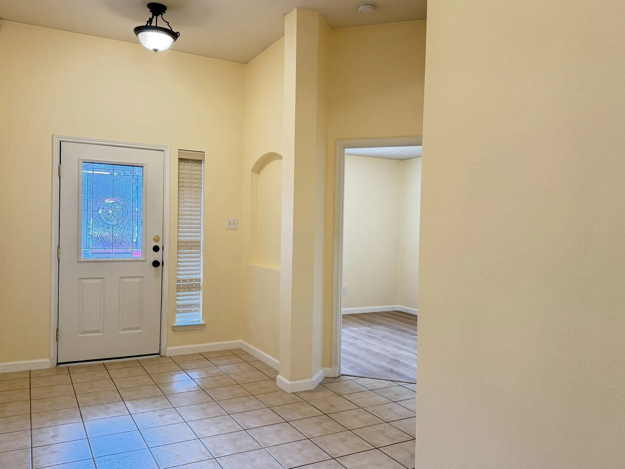Entryway featuring tile flooring, vaulted ceilings, a decorative wall niche, and an exterior door with a leaded glass insert