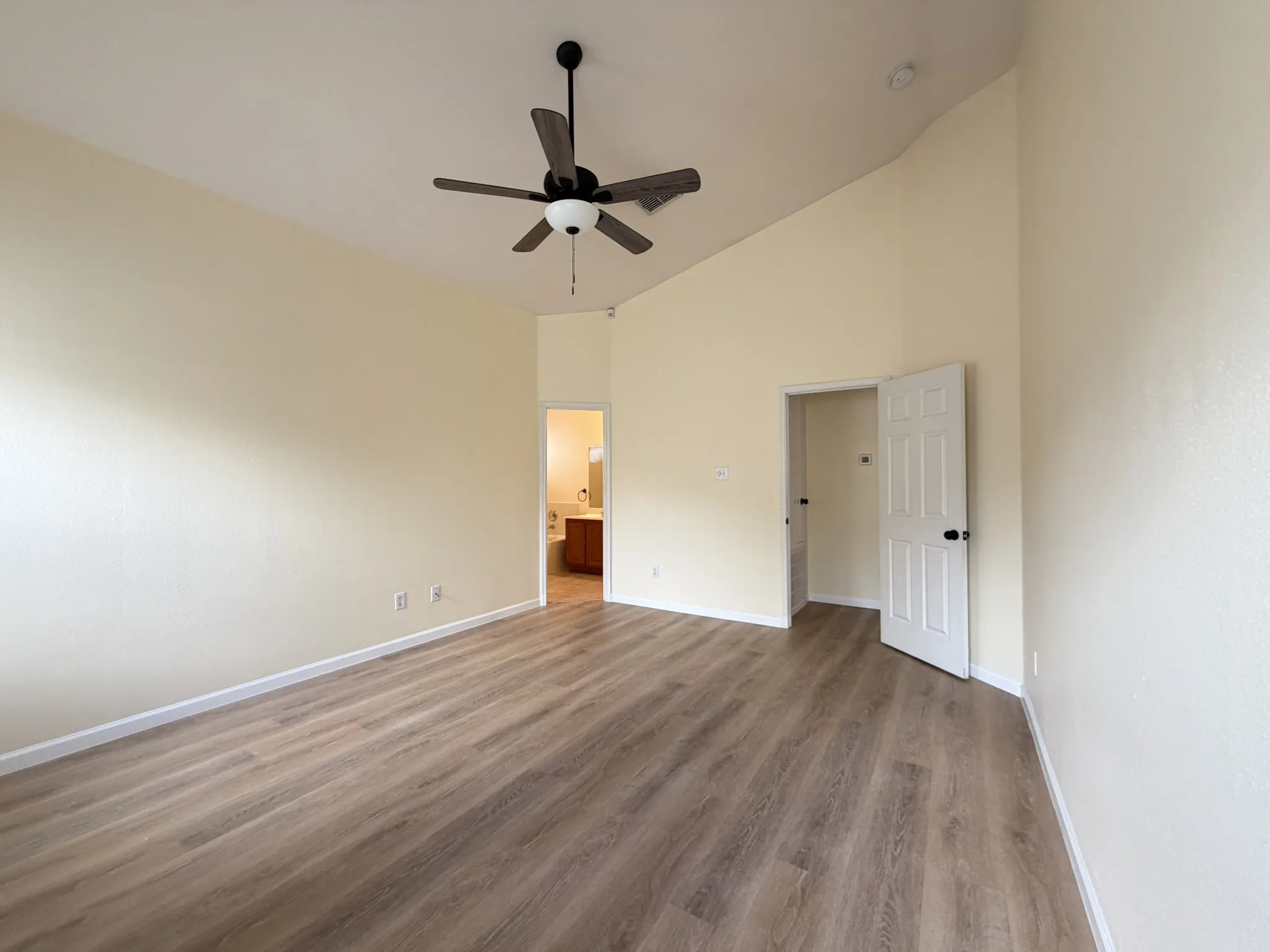 Room featuring vaulted ceilings, wood-finish flooring, and a ceiling fan with integrated lighting