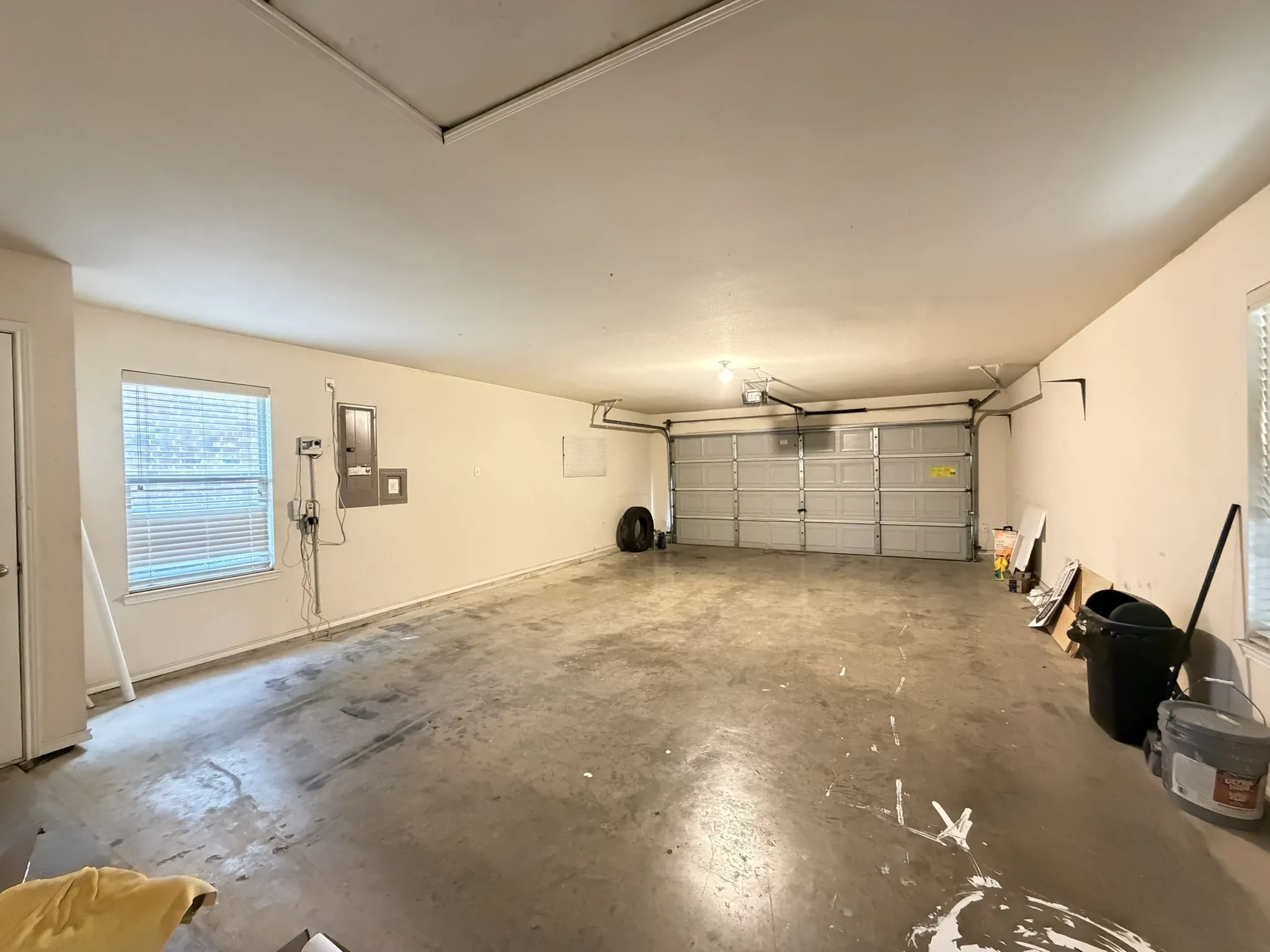 Attached garage featuring concrete flooring, a multi-panel overhead door, and a wall-mounted electrical service panel