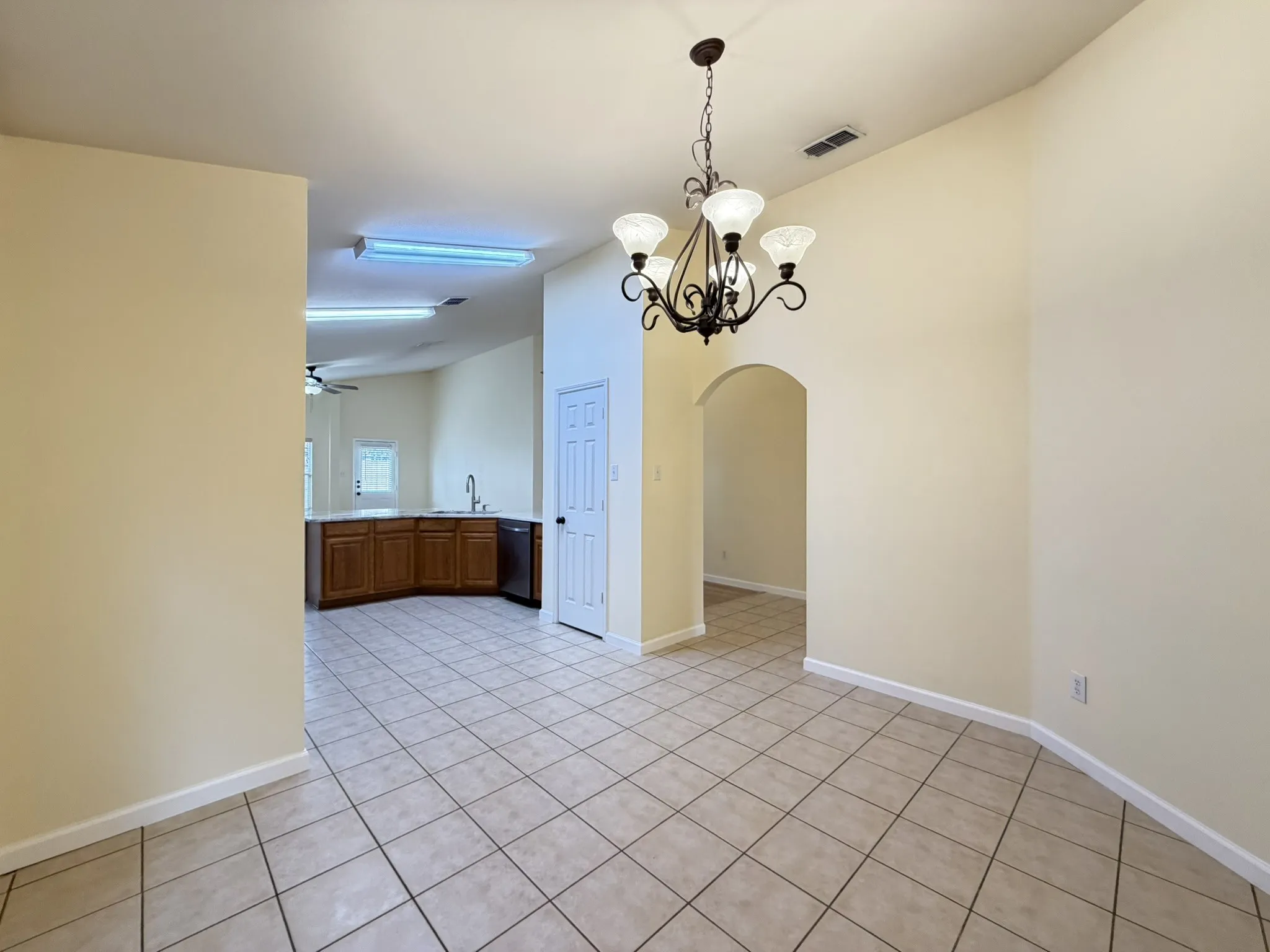 Vaulted ceilings, ceramic tile flooring, decorative wrought-iron chandelier, and arched doorway