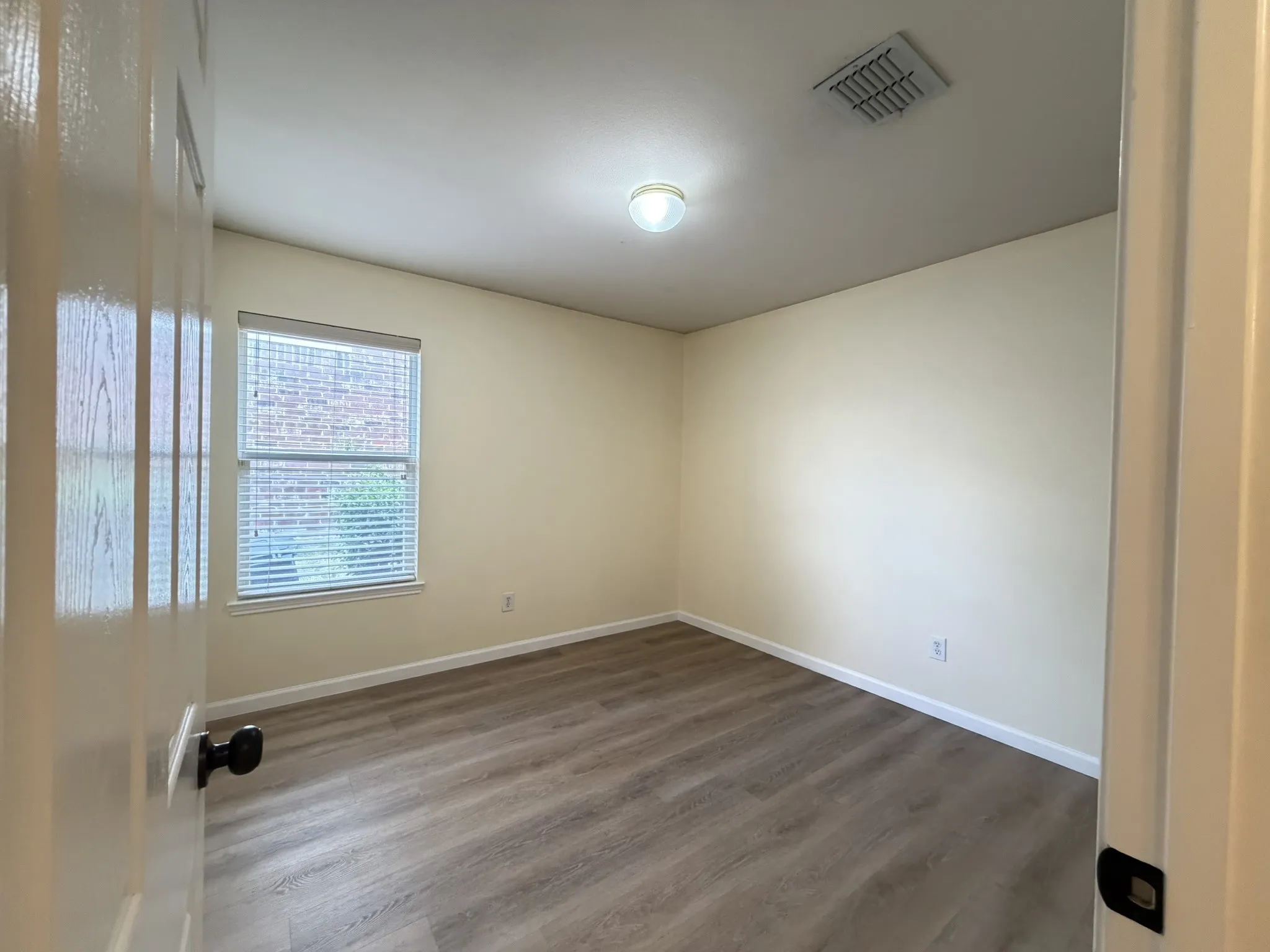 Room featuring wood-finish flooring, neutral wall paint, and a window with fitted blinds