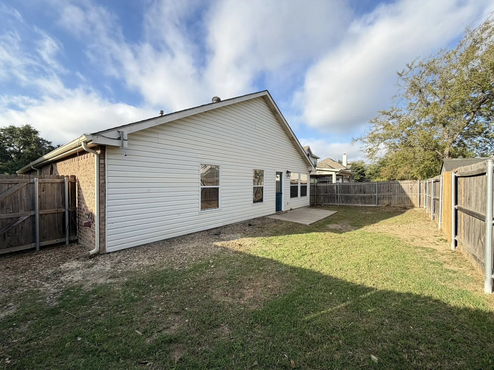 Rear exterior featuring siding and brick masonry, concrete patio, and fenced yard
